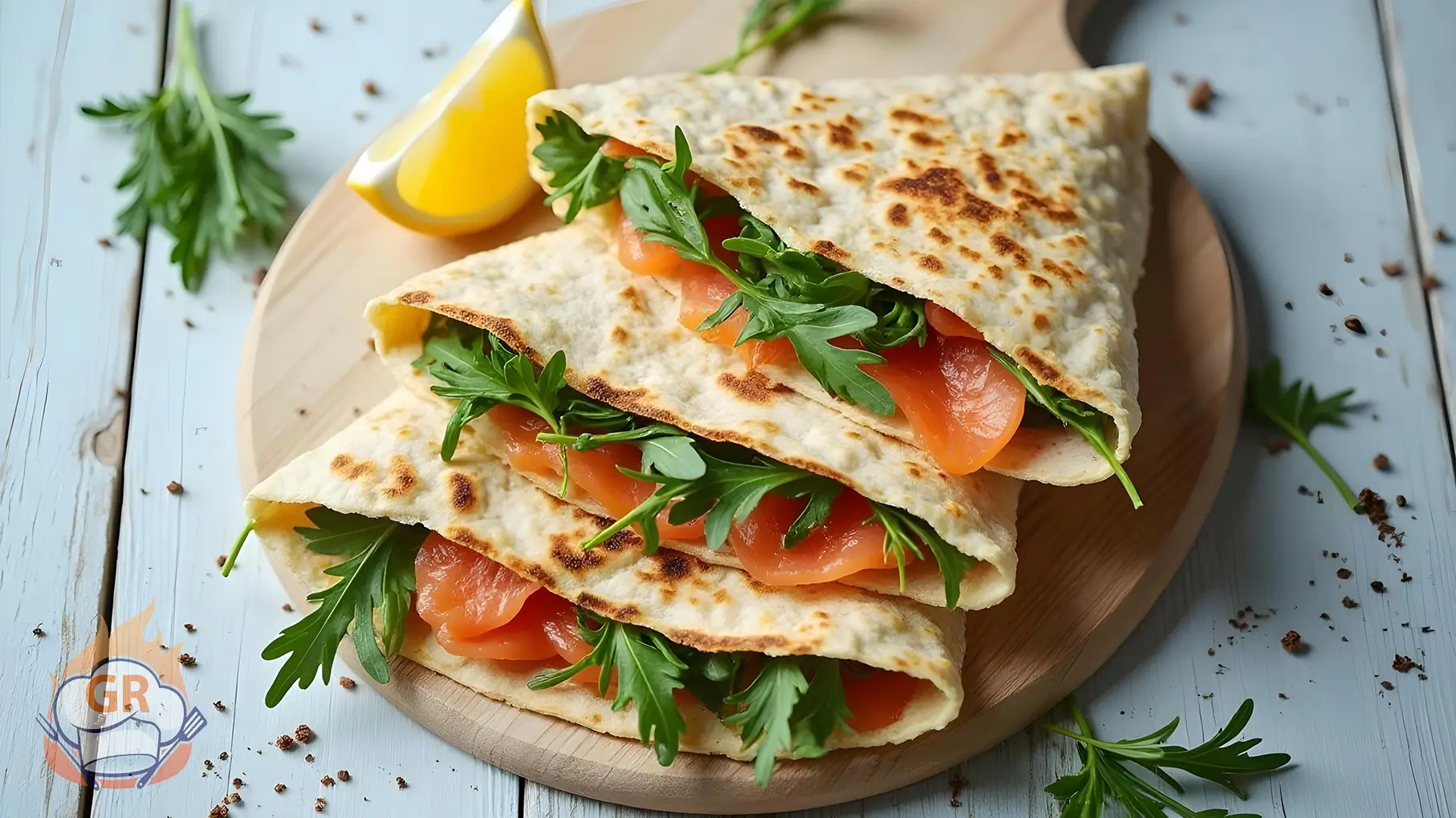 Piadina con salmone affumicato, formaggio cremoso, rucola e avocado, guarnita con erbe fresche.